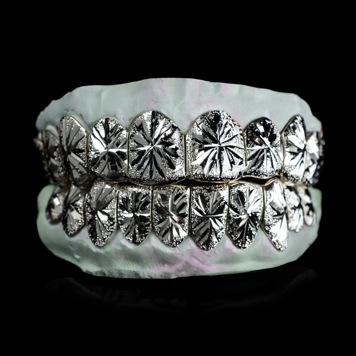 Silver starburst cut dental grillz with diamond dust texture and gold edges on mold