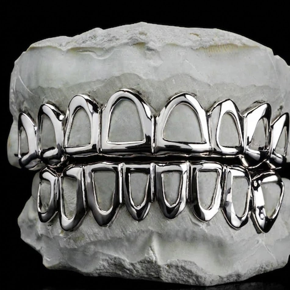 Silver custom open-face grillz with sleek contours on white dental mold
