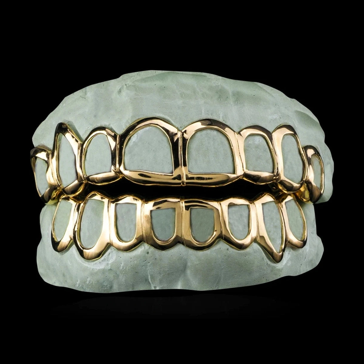 Custom open-face gold grillz set on dental mold showing polished finish