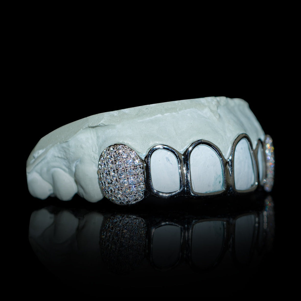 Side view of open face gold grillz on dental mold with diamond teeth