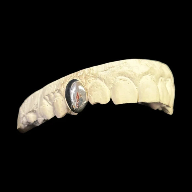 Silver single tooth grillz with red-orange tint on beige model