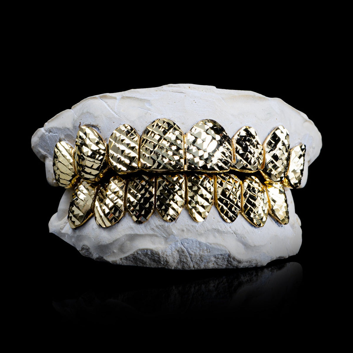 Gold plated diamond cut grillz with 8 top and bottom teeth on white dental mold