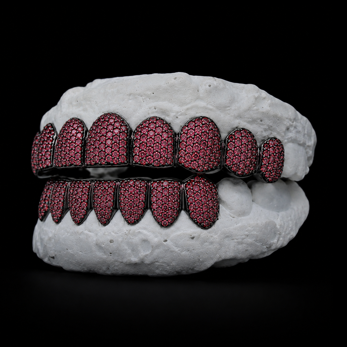 Angled shot of black gold-plated grillz featuring vibrant red gemstone pavé detail