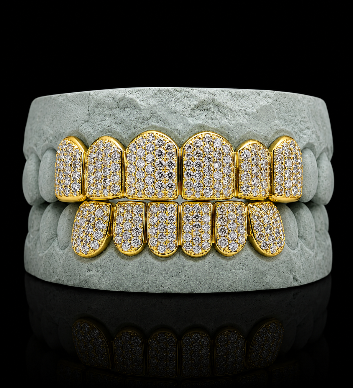 Iced out yellow gold grillz fitted on grey dental mold for size reference