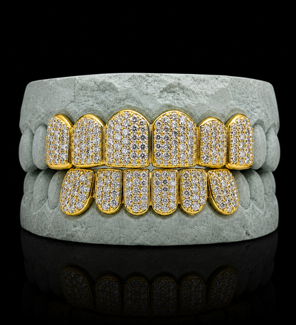 Iced out yellow gold grillz fitted on grey dental mold for size reference